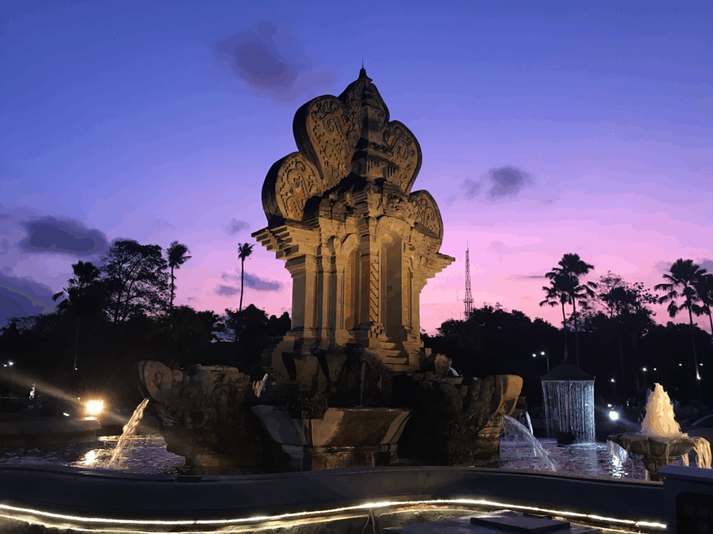 Dramatic sunset over intricate temple with fountains.