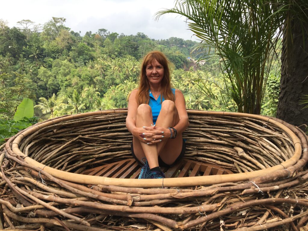 Smiling person in large wooden nest, jungle background.